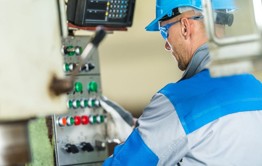 Lavoratore al pannello di comando di un macchinario industriale